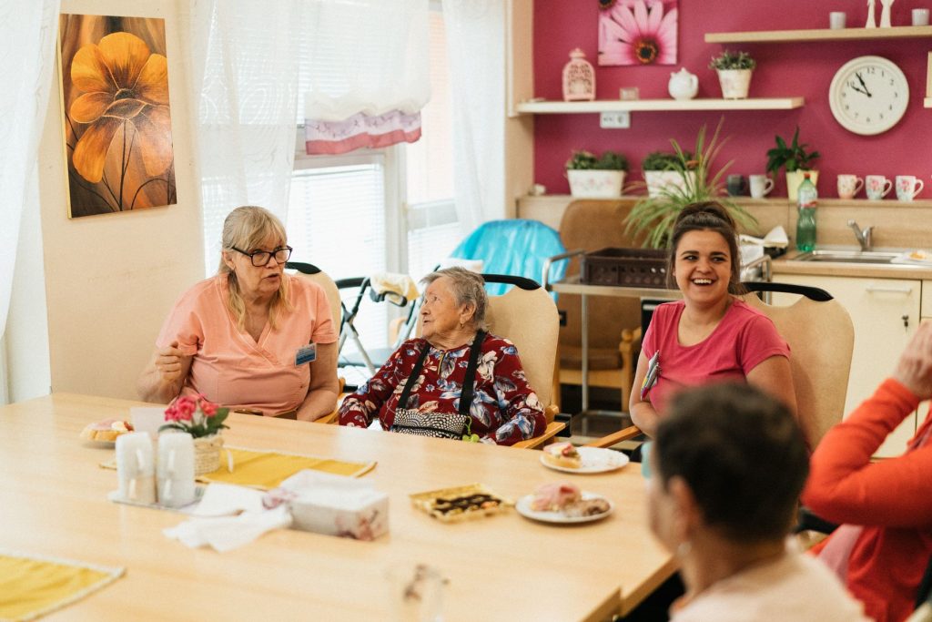 Drei Frauen sitzen gemeinsam am Tisch in einer häuslichen Umgebung