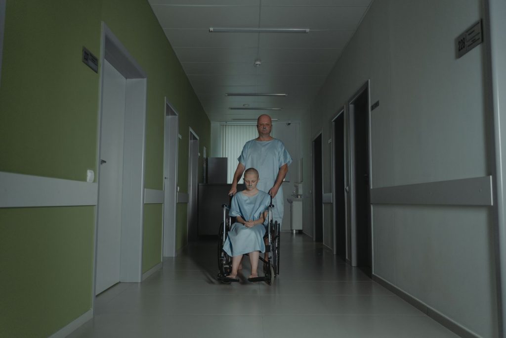 Patient wird im Rollstuhl durch einen Klinikflur begleitet